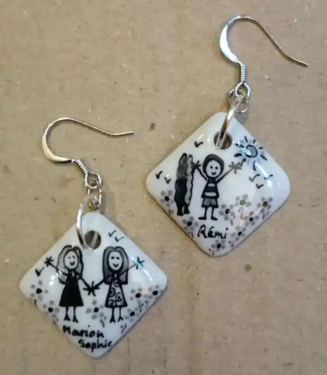 Boucles d'oreilles carrées en porcelaine personnalisées dans un style naïf en noir et gris par des enfants.