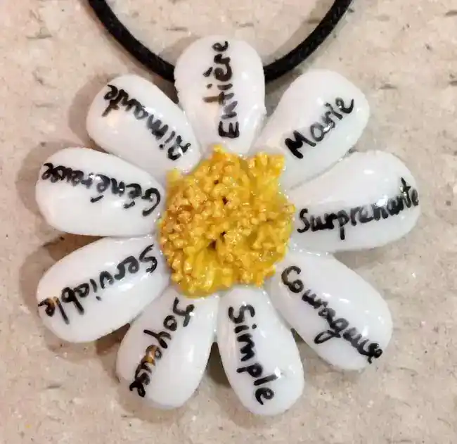 Pendentif marguerite en porcelaine personnalisé par des mots et les prénoms des petits enfants.