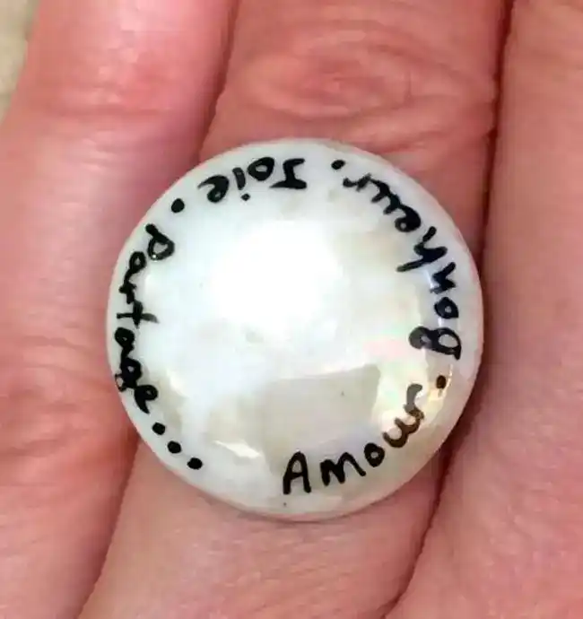 Bague ronde personnalisée par des mots sur un fond nacré.