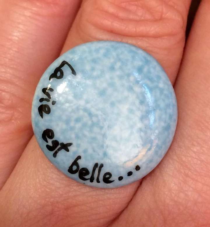 Bague ronde personnalisée par une phrase sur un fond bleu turquoise.