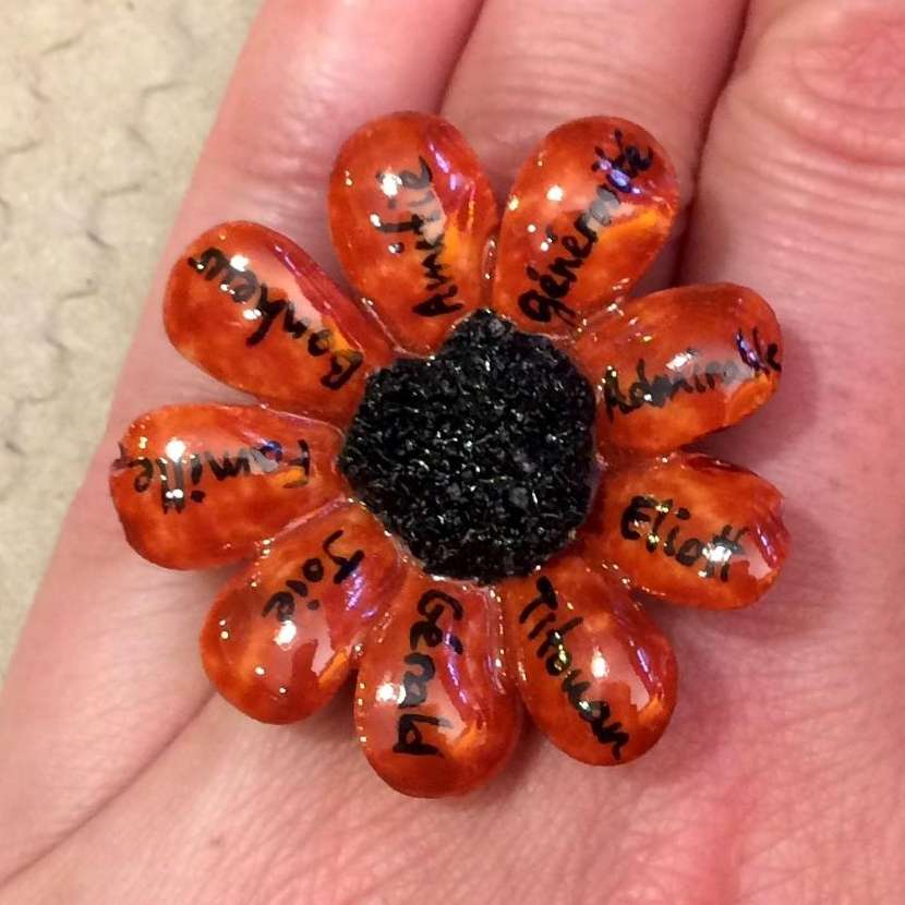 Bague marguerite personnalisée par des mots doux sur des pétales rouges et un coeur noir.