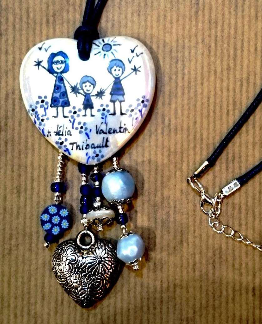 Pendentif coeur en porcelaine et breloques personnalisé dans un style naïf dans les tons bleus.