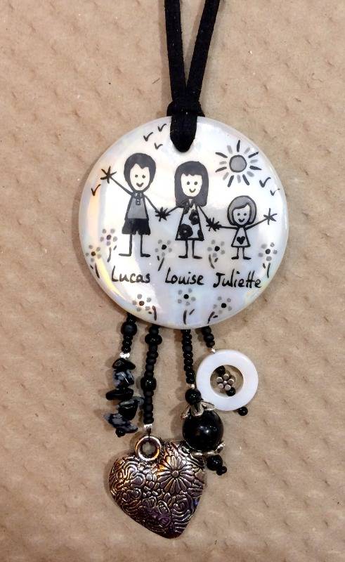 Pendentif rond en porcelaine et breloques personnalisé dans un style naïf en noir et gris fond nacré.