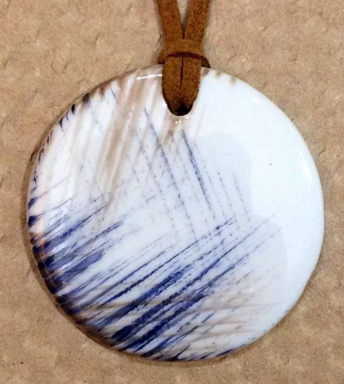 Pendentif rond en porcelaine personnalisé par des lignes bleue et taupe.